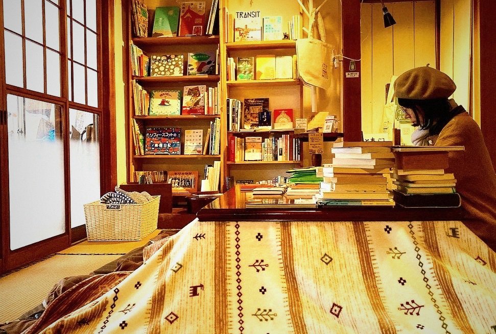 NEMARUの本棚の前で読書する人 ― 約1,500冊の蔵書がある古民家宿